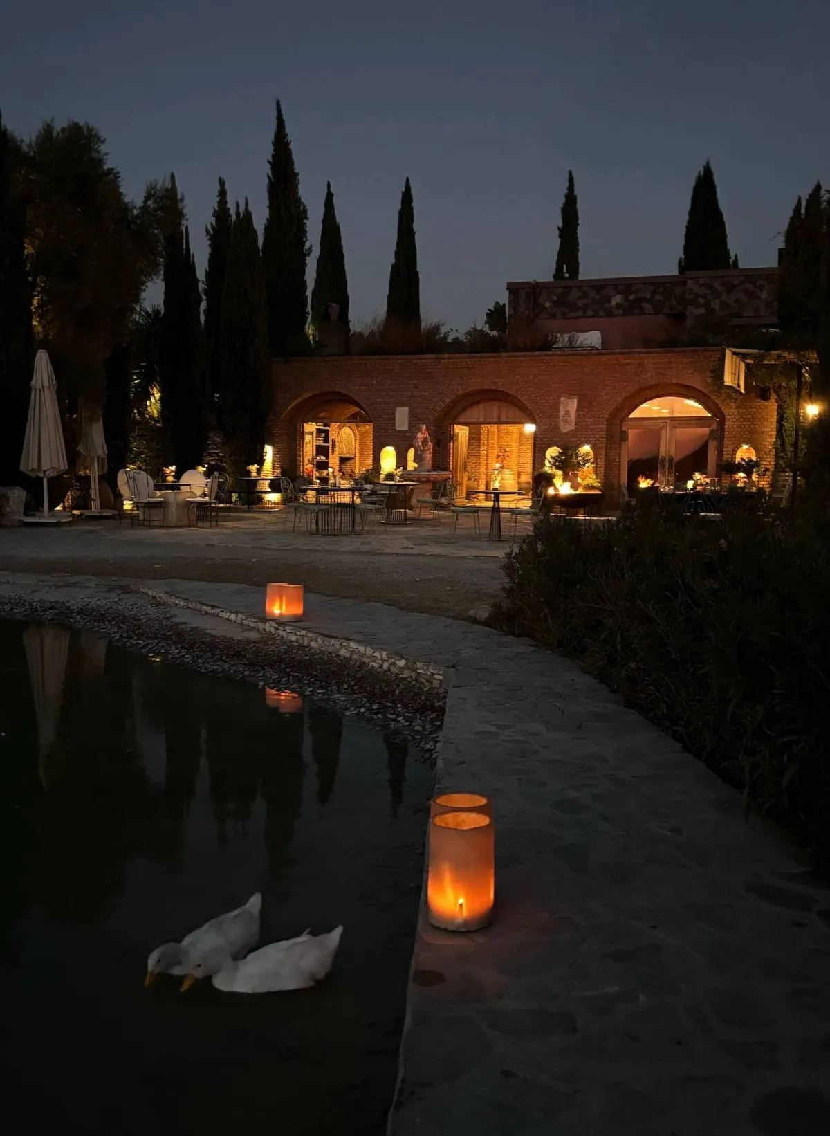 Karnas Vineyards winery lit up in the evening, with candles by the pond